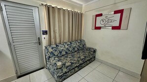 Una habitación con una puerta corredera cerrada, un sofá floral, piso de baldosas y un cuadro colgado en la pared.