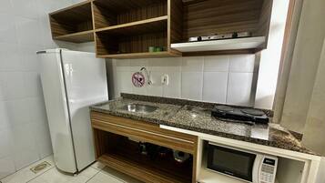 Una cocina con microondas integrado, un lavabo y un refrigerador.