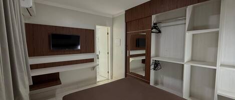 A bedroom with a TV, built-in shelves, a wardrobe, and a bed.