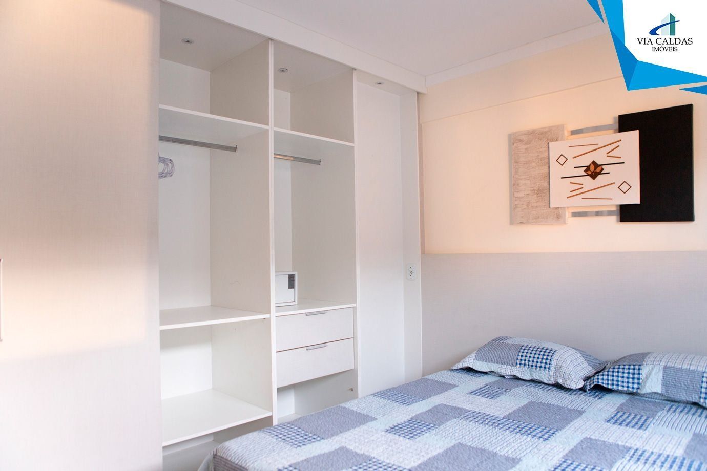 A bedroom with a bed, a wardrobe, and a wall-mounted artwork.