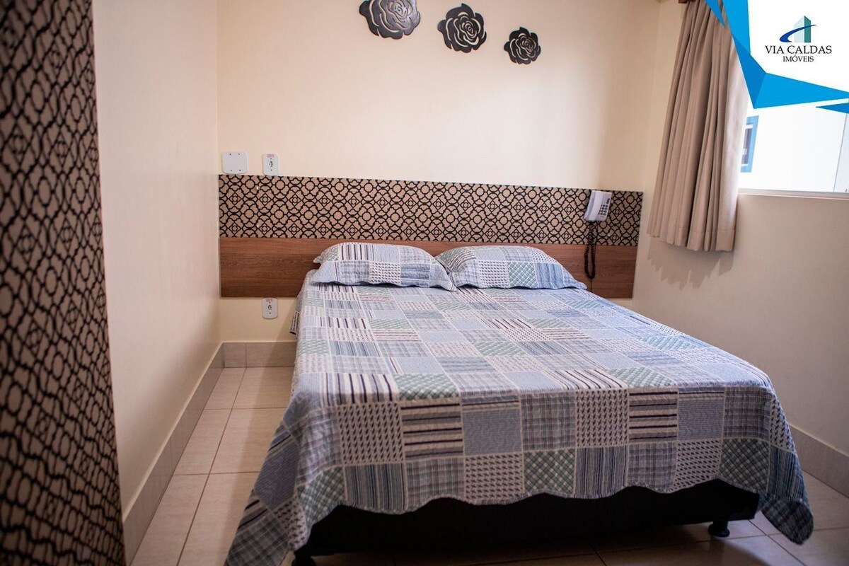 Un dormitorio con colcha estampada, cabecera de madera y decoración en la pared.