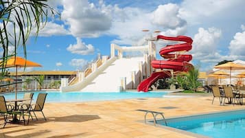 Ein Poolbereich mit Wasserrutsche, Liegestühlen und Sonnenschirmen.