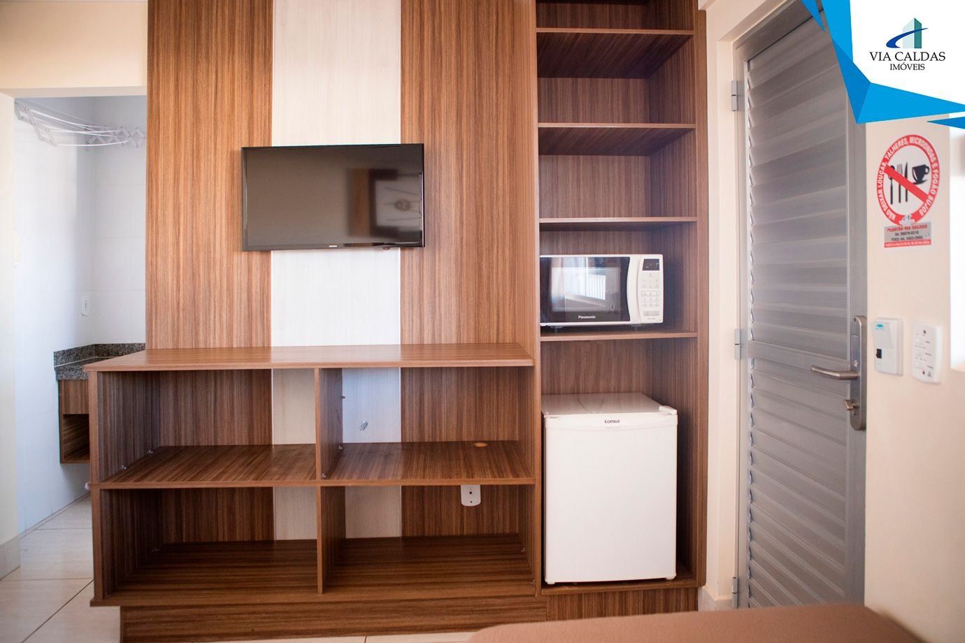 A kitchenette with wooden cabinetry, a microwave, and a refrigerator.
