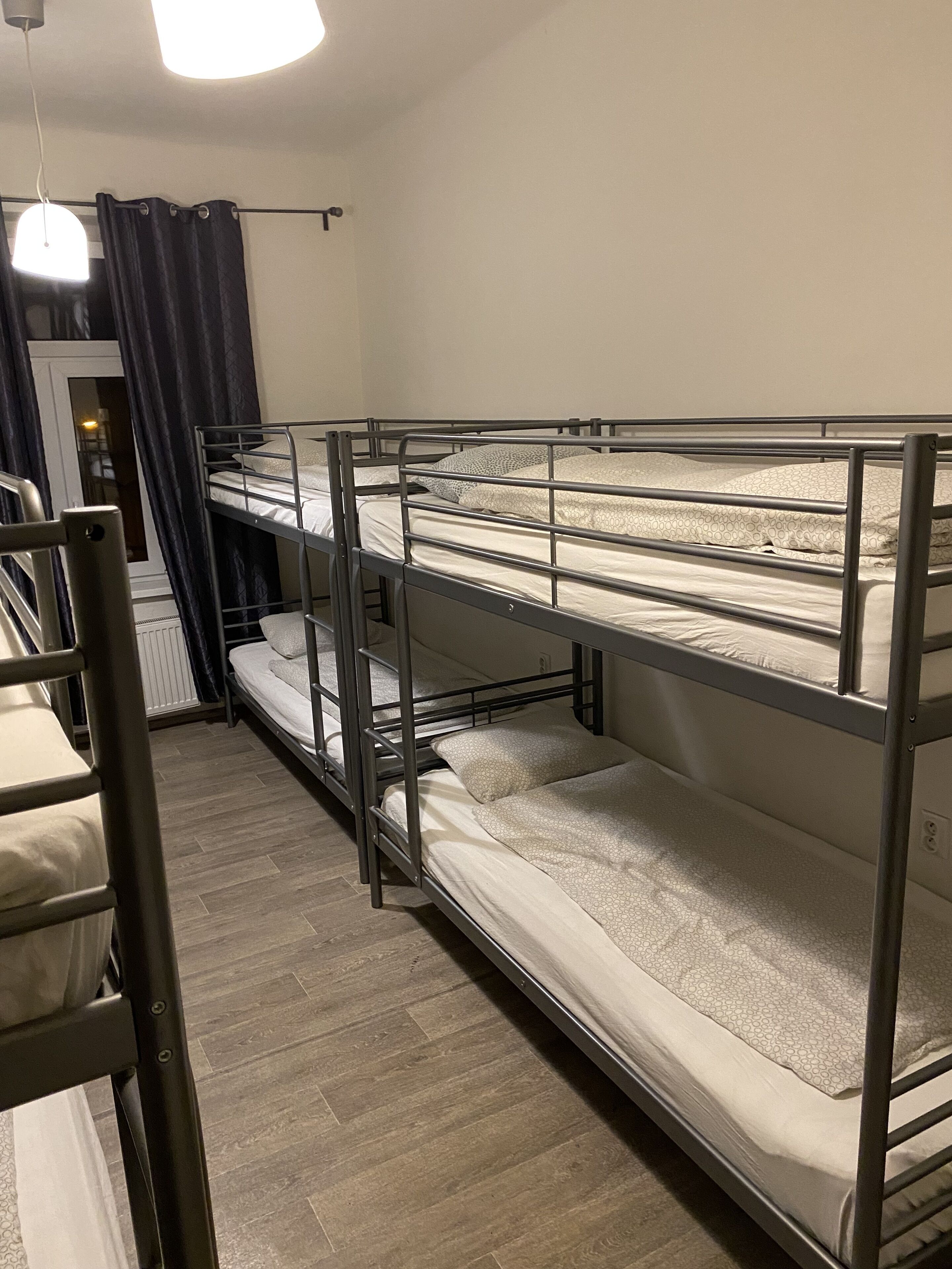 Dormitorio con literas, una ventana, una puerta y una lámpara.