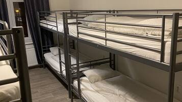 Dormitorio con literas, una ventana, una puerta y una lámpara.