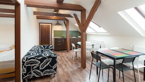 A loft-style bedroom with a bed, a sofa, and a dining area with a table and chairs. - Easy Housing Hostel (Prague)