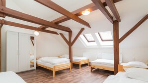 A room with wooden beams, skylights, and three wooden beds with white bedding. - Easy Housing Hostel (Prague)