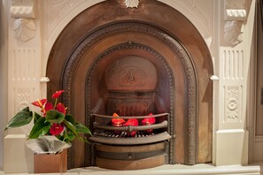 Una chimenea con un arco decorativo y un florero con flores rojas sobre la repisa.