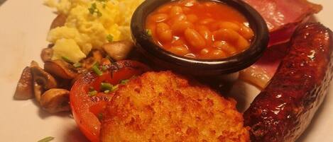 A plate of breakfast food including eggs, sausages, and beans.