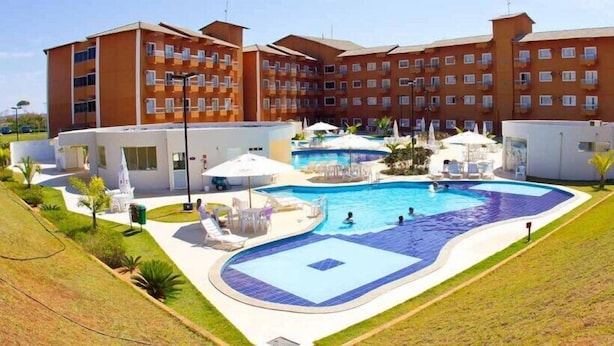 Un hotel con una amplia piscina, varios balcones y zonas de estar al aire libre.