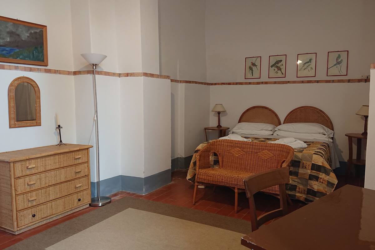A bedroom with a bed, dresser, lamp, and wall art.