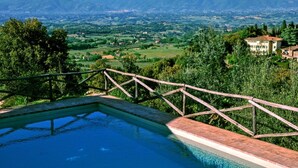A swimming pool with a wooden deck and a view of a mountainous landscape. - Petrolo (Bucine)