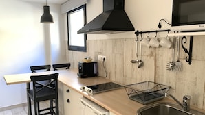 A modern kitchen with a wooden countertop, a black range hood, a microwave, and a sink. - Gorbea Suites (Monachil)
