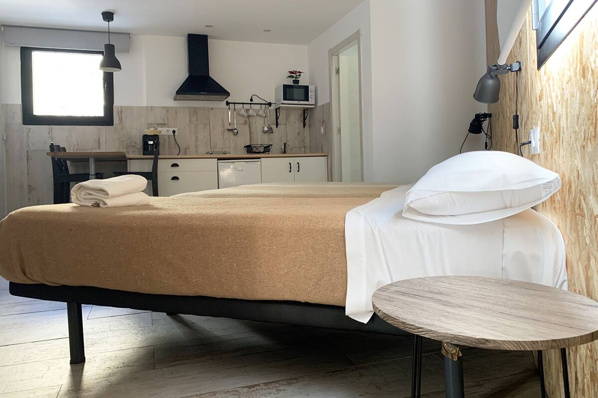 Un dormitorio moderno con cama, mesita de noche y vistas a la cocina.