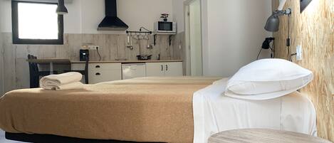 Un dormitorio moderno con cama, mesita de noche y vistas a la cocina.