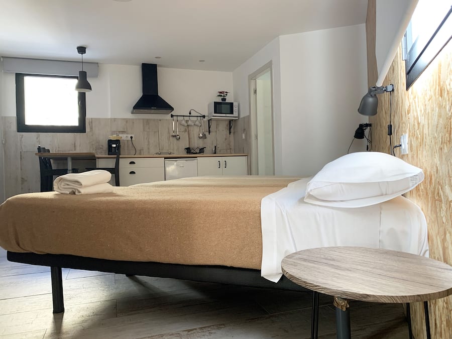 Un dormitorio moderno con cama, mesita de noche y vistas a la cocina.