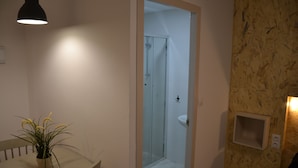 A bathroom with a white sink, a glass shower door, and a potted plant on a curved countertop. - Gorbea Suites (Monachil)