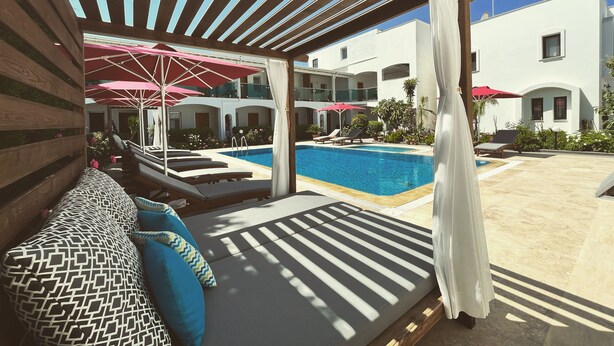 A poolside area with lounge chairs, umbrellas, and a covered seating area. - The Losh (Bodrum)