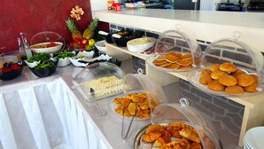 A buffet with various food items covered in protective domes, including fruits, pastries, and other dishes. - The Losh (Bodrum)
