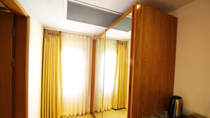 A hotel room with a wooden wardrobe, a mirror, a coffee maker, and a tiled floor. - The Losh (Bodrum)