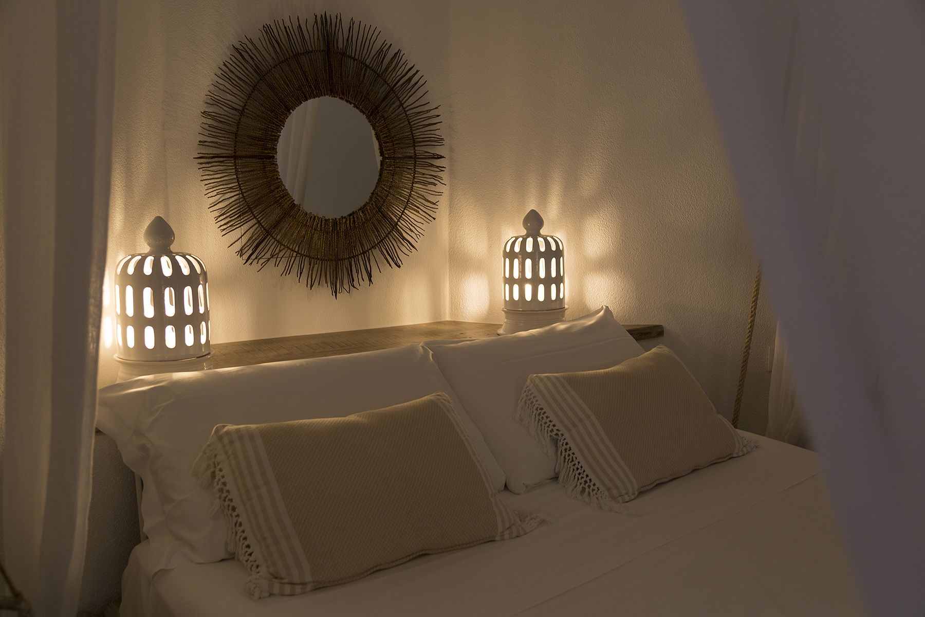 A bedroom with a bed, two wall-mounted lamps, and a mirror.