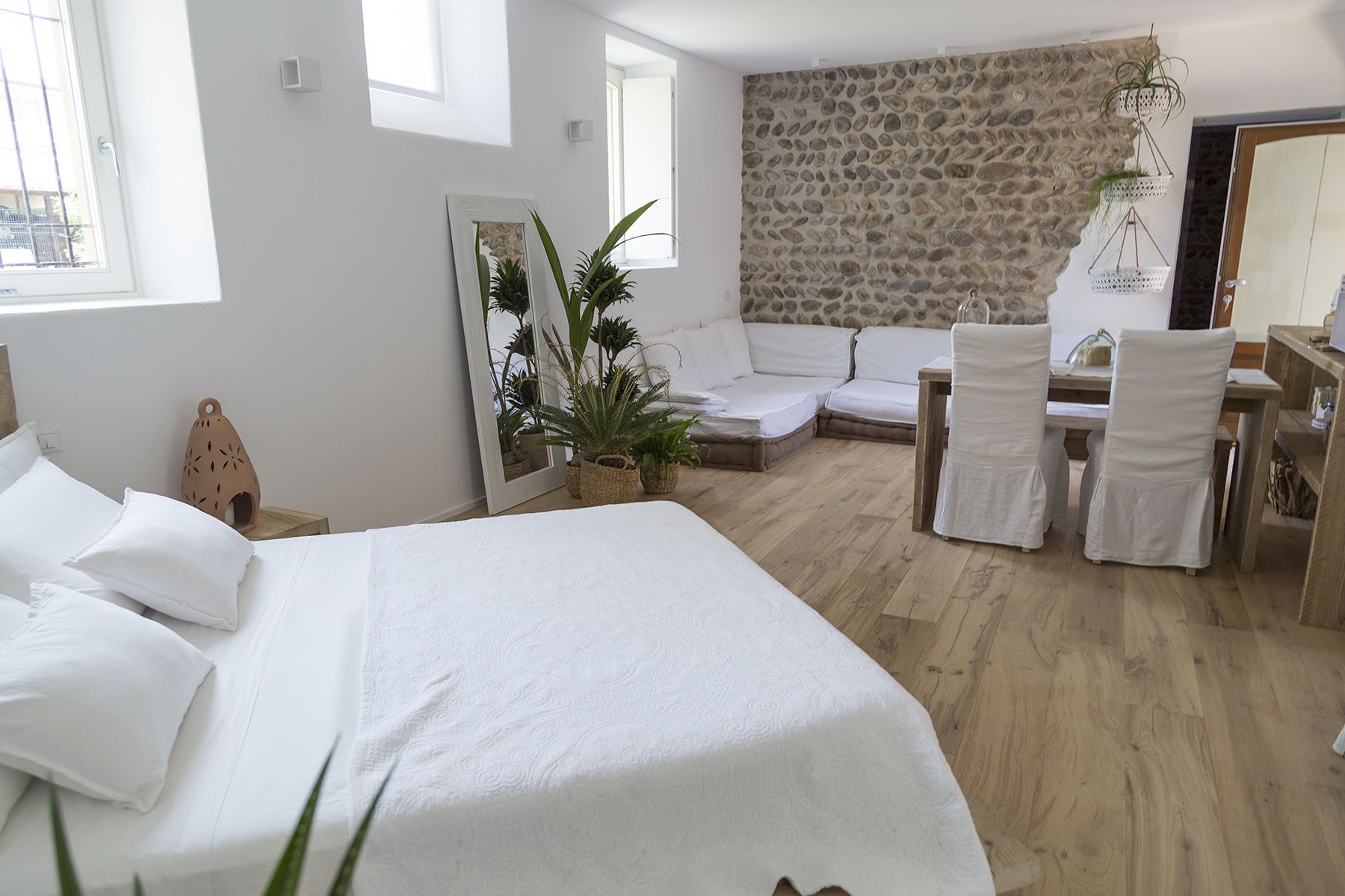 Une chambre moderne avec un grand lit, un mur en pierre, un canapé et un coin repas avec des chaises.