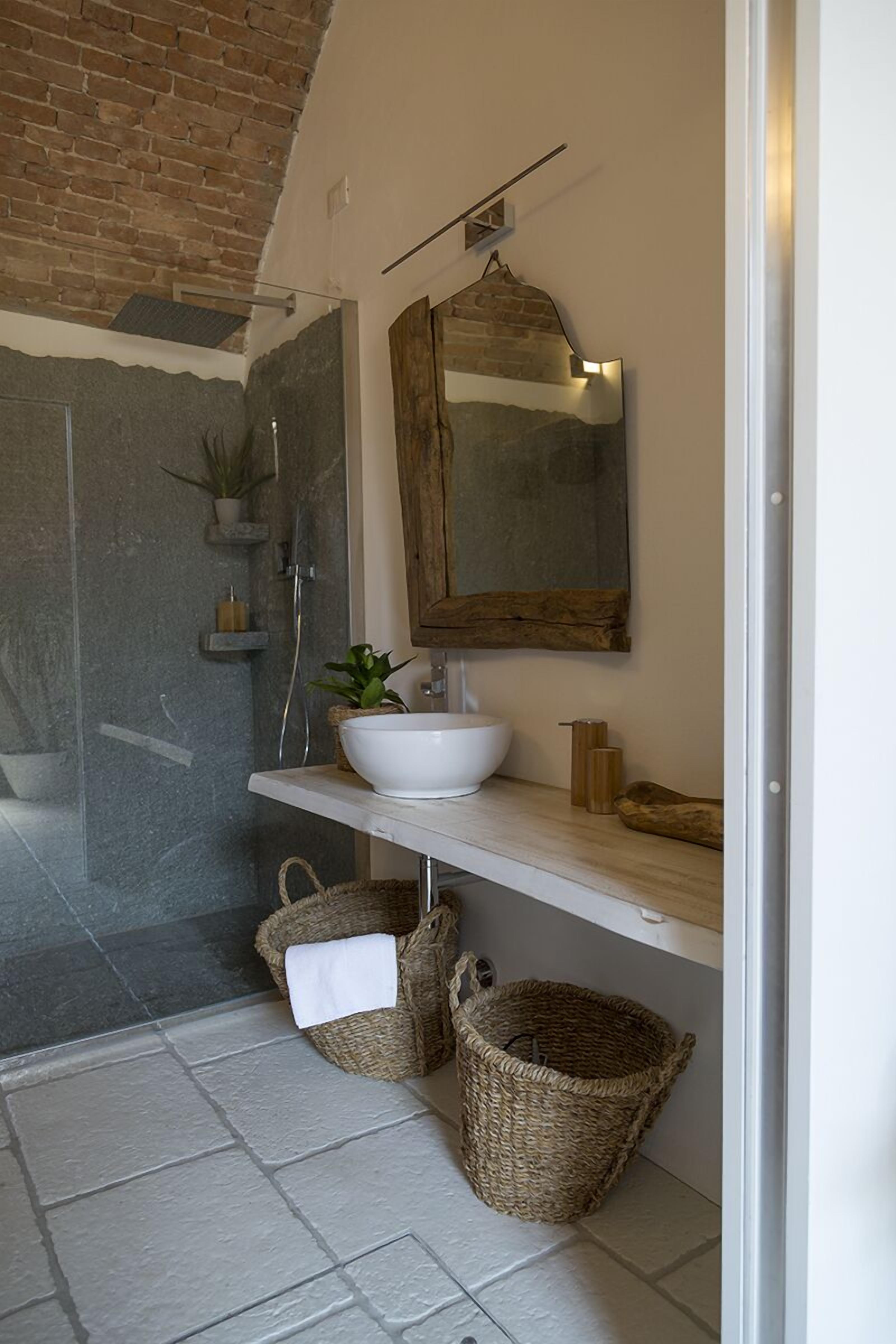 Un baño con lavamanos blanco, espejo de madera y zona de ducha.
