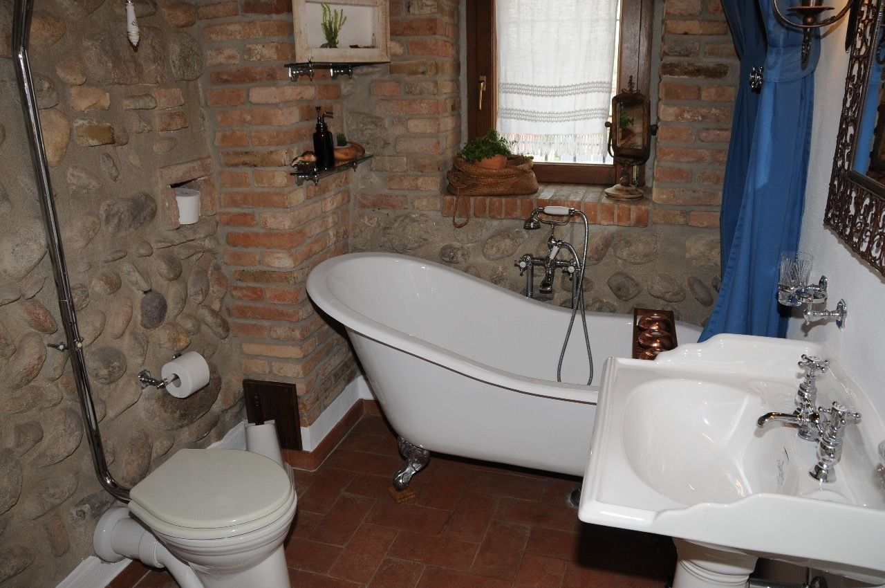 Ein Badezimmer mit Badewanne auf Füßen, einem weißen Waschbecken und einer Toilette.
