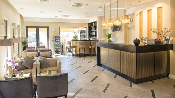 Un vestíbulo moderno con una recepción, zona de estar y un bar.