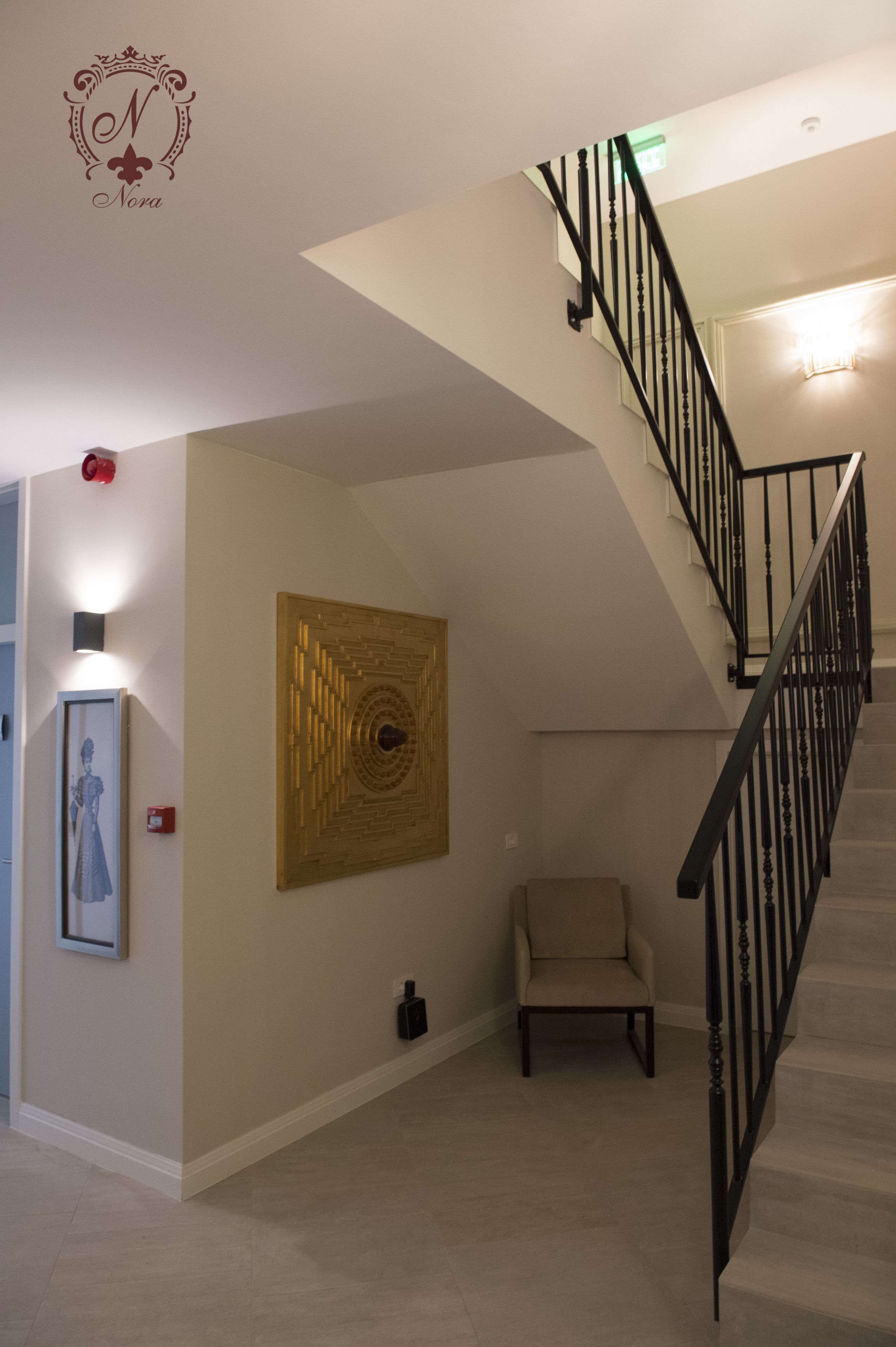 A staircase with a black railing, a framed picture on the wall, and a chair in the corner.