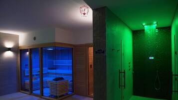 A spa room with a sauna, a massage area, and a shower.