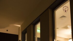 Fachada moderna de un edificio por la noche, con ventanas iluminadas y un jardín bien cuidado.