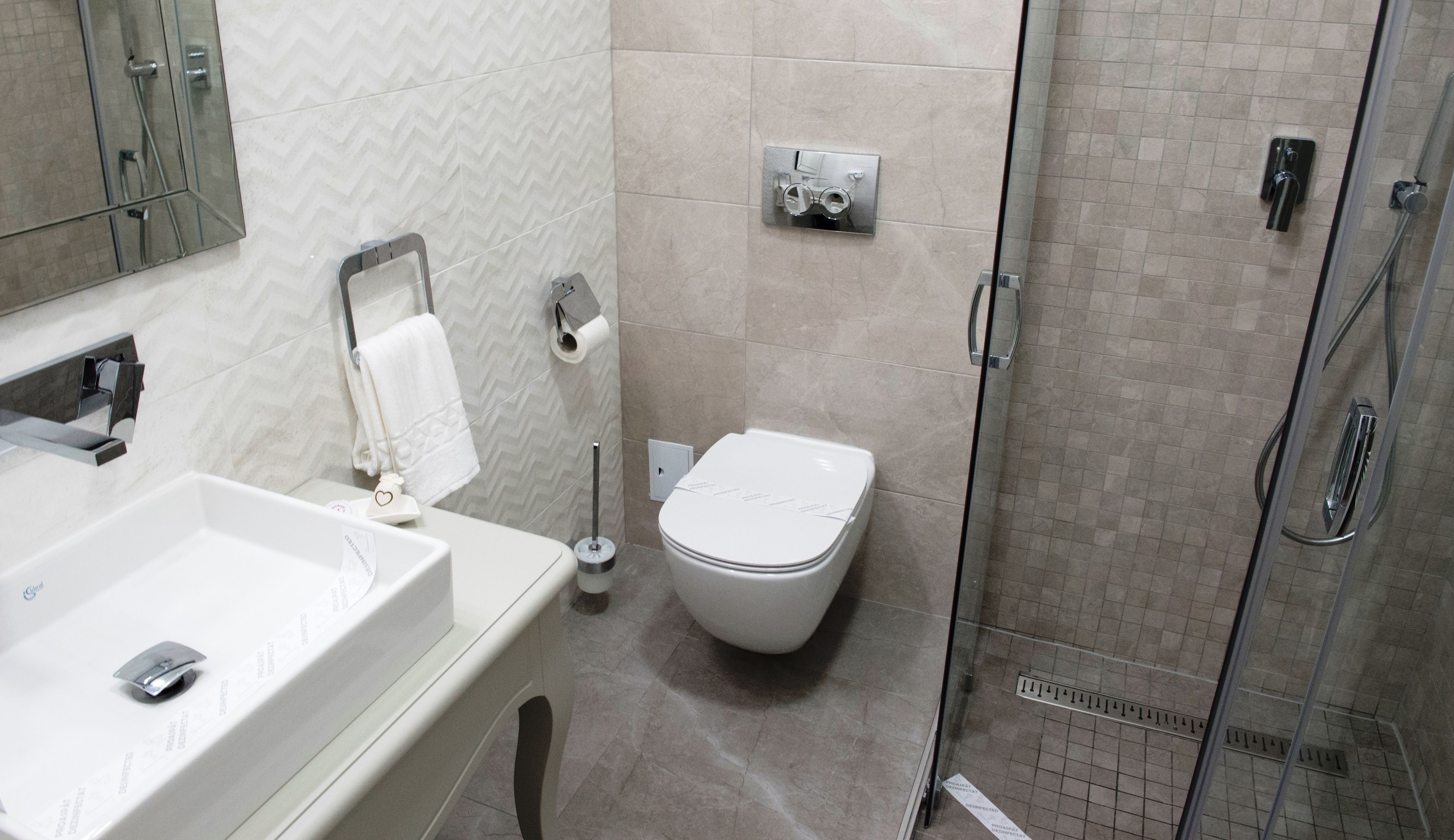 A modern bathroom with a white sink, toilet, and shower.