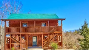 A two-story log cabin with a green roof, a front porch, and a staircase leading to the second floor. - Smoky Mountain Lodge (Pigeon Forge)