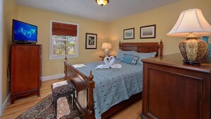 A bedroom with a bed, a television, a lamp, and a window with blinds. - Gettin Cozy (Sevierville)
