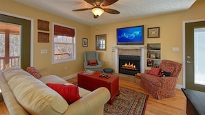 A living room with a fireplace, a ceiling fan, and a television. - Gettin Cozy (Sevierville)