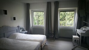 Quarto com duas camas, uma escrivaninha, uma cadeira e um radiador.