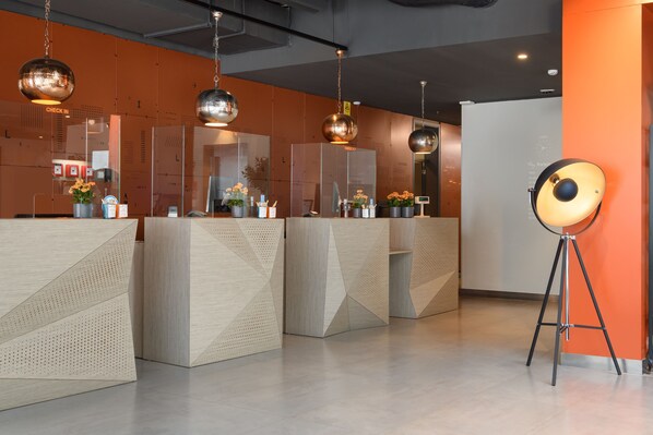A reception area with modern, geometric reception desks, a standing lamp, and a check-in counter.