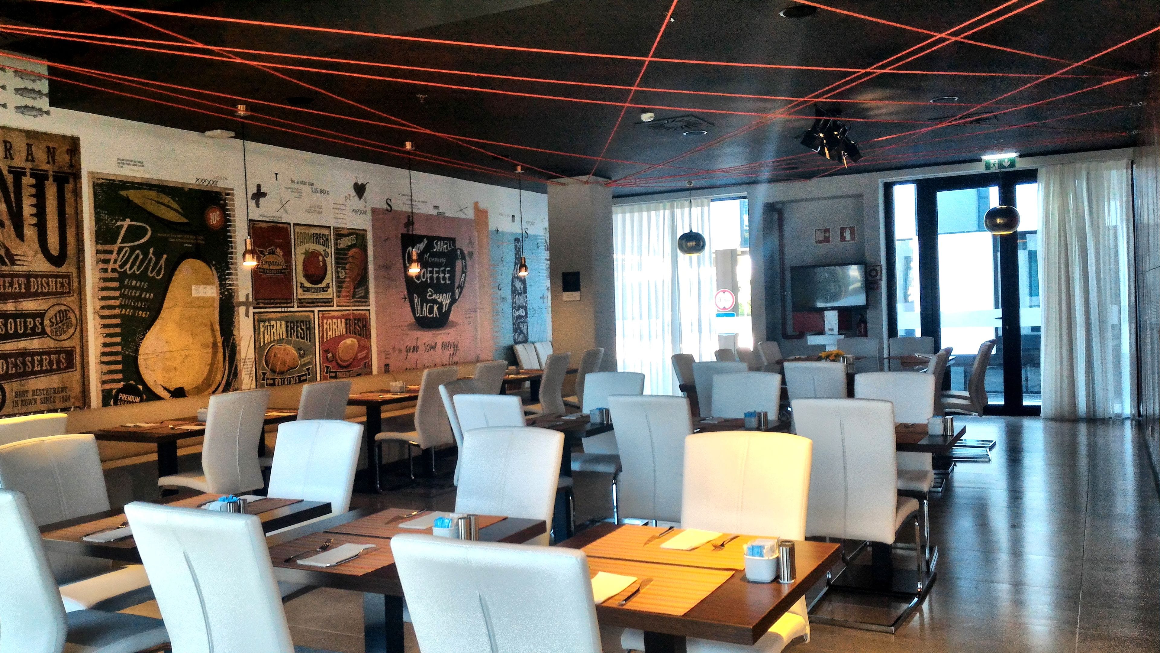 En restaurant med et moderne interiør, borde og stole anrettet til spisning.