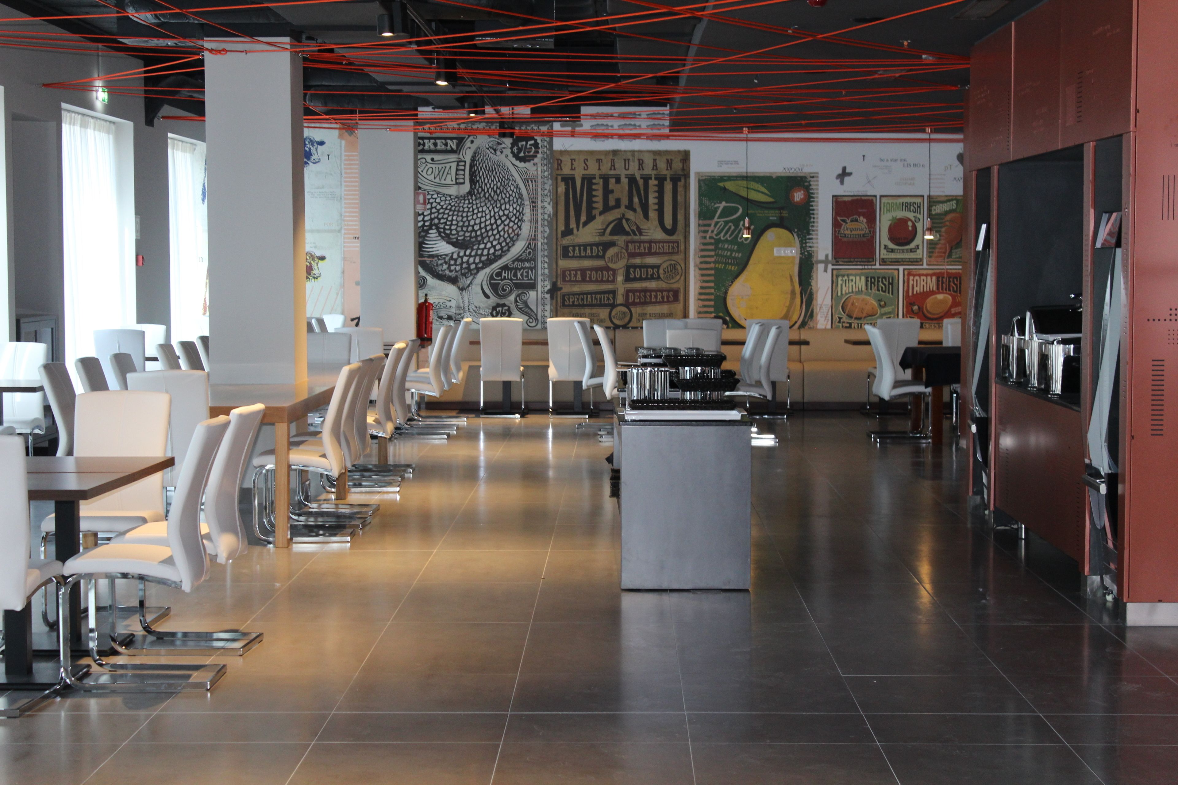 A modern restaurant interior with white chairs, a central island, and a menu wall.