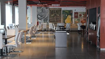 A modern restaurant interior with white chairs, a central island, and a menu wall.