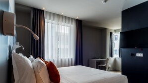 Una habitación de hotel con una cama grande, un escritorio y una silla.