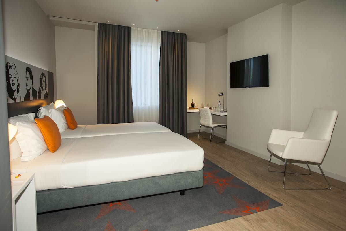 Moderni hotellihuone, jossa on suuri sänky, työpöytä, tuoli ja televisio.
