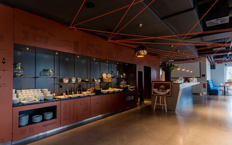 A modern kitchen with a long counter, various kitchenware, and a hanging light fixture.