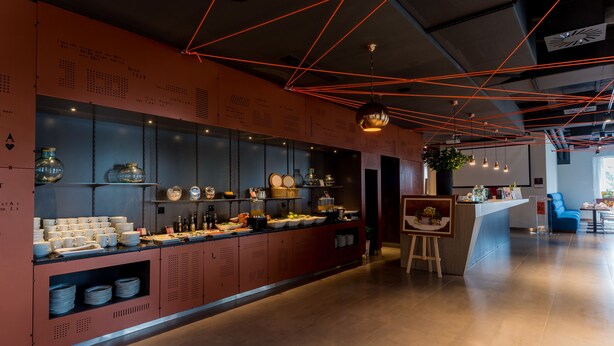 Una cocina moderna con una encimera larga, distintos utensilios de cocina y una lámpara colgante.