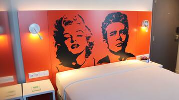 Een hotelkamer met een bed, een wandlamp en een stopcontact.