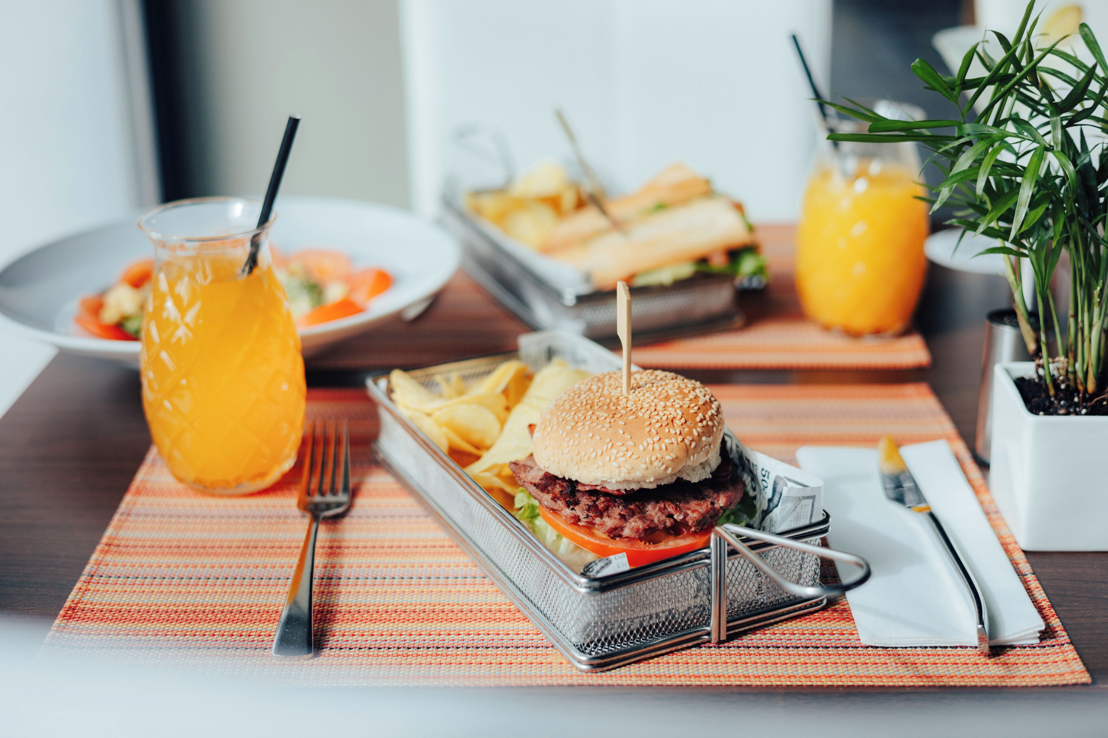 Un plat amb una hamburguesa, patates fregides i una beguda sobre una taula.