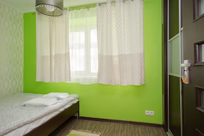 A room with a bed, a window with patterned curtains, a green wall, and a door with a mirror and a hanging ornament. - ShortStayPoland Solidarnosci B8 (Warsaw)