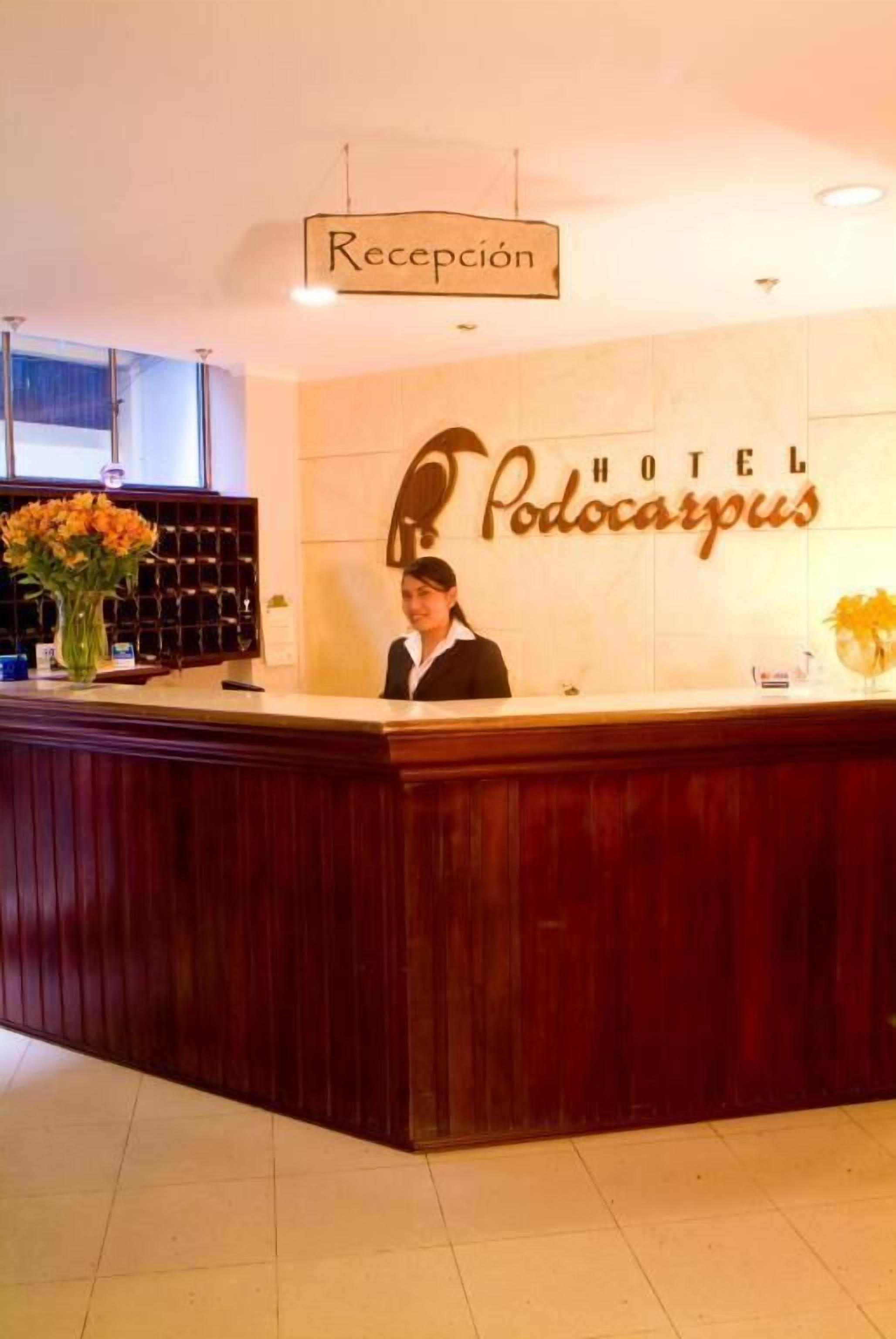 Mostrador de recepción en el Hotel Podocarpus con un cartel que indica la zona de recepción.