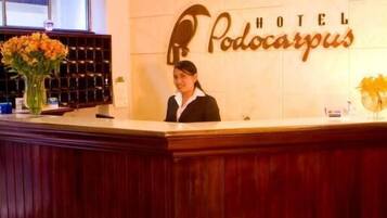 Mostrador de recepción en el Hotel Podocarpus con un cartel que indica la zona de recepción.